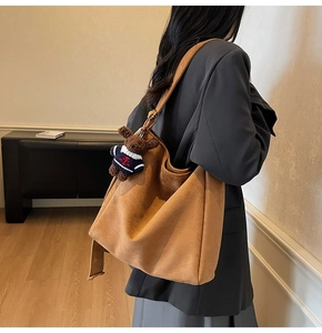 Détail du sac seau en daim marron avec bandoulière et pendentif en forme d'ours en peluche