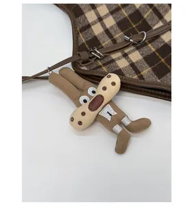 Close-up of brown checkered tote bag featuring a detachable plush rabbit charm accessory