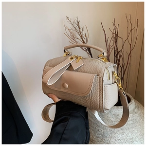 Dettaglio della borsa Boston beige con grana litchi, fibbie dorate e tracolla larga