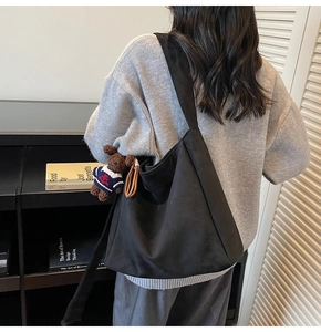 Détail d'un grand sac cabas noir mat avec un joli pendentif ours en peluche rétro