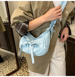 Détail du sac bandoulière bleu clair avec nœud et bandoulière plissée sur trench kaki