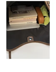 Top-down view of large brown leather tote interior holding laptop, books, and umbrella