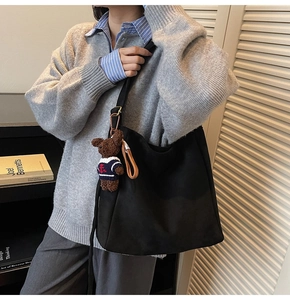 Vue détaillée du sac seau noir mat avec un joli pendentif en peluche d'ours brun