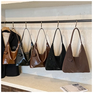 Selection of large leather and suede hobo tote bags displayed on a black metal hanger rack