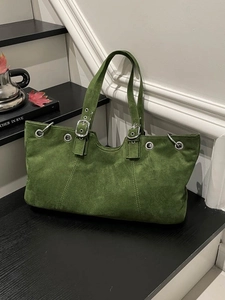 Green suede tote bag with metal eyelets and adjustable strap in a retro autumn style
