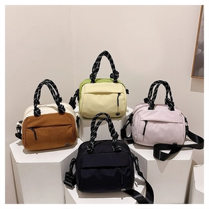 Detail view of colorful multi-pocket crossbody bags on a geometric display stand