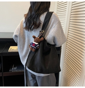Détail du sac seau noir mat avec bandoulière réglable et pendentif ours en peluche
