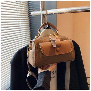 Dettaglio di una borsa marrone con motivo litchi appesa e finiture in metallo dorato