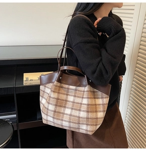 Détail du sac cabas vintage à carreaux avec brides en cuir marron porté par un mannequin