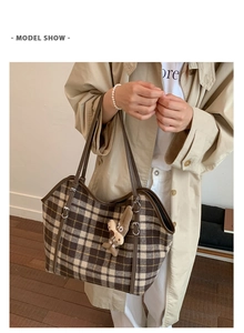 Detail of checkered tote bag with brown shoulder straps and cute plush rabbit charm
