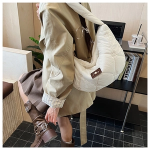 Détail du sac hobo blanc matelassé en forme de cœur avec perles et accents en cuir