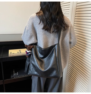 Détail du sac seau noir mat avec large bandoulière et pendentif ours en peluche marron