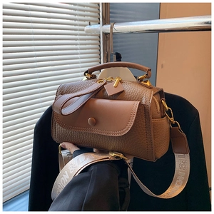 Dettaglio borsa in pelle marrone motivo litchi con finiture dorate e tracolla larga