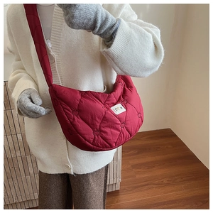 Détail du sac demi-lune rouge matelassé avec surpiqûres en cœur et écusson logo