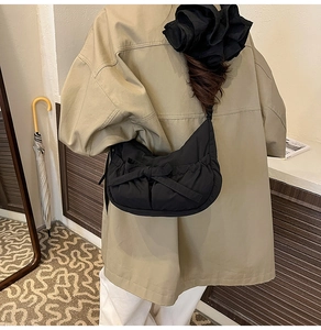 Détail du sac croissant en tissu noir avec grand nœud et plis portés par le mannequin