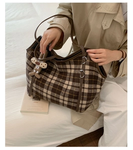 Detail of checkered tote bag in brown wool with leather handles and bunny charm