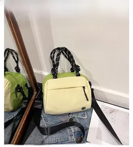 Detail of color-block nylon tote bag with woven rope handles on denim jacket