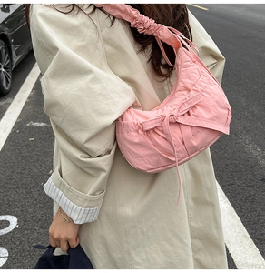 Vue latérale d'un grand sac bandoulière en nylon plissé rose porté par un mannequin