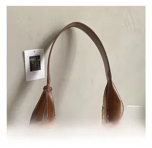 Close-up of the vintage brown hobo bag showing the glossy leather texture and strap