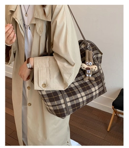 Detail of vintage plaid tote bag with brown leather straps and cute plush pendant