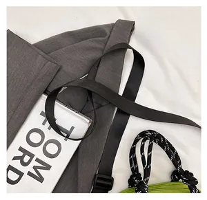 Detail view of the black nylon shoulder strap and woven handle on the green handbag