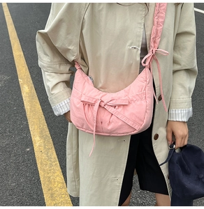 Détail du sac croissant matelassé rose avec texture plissée et un nœud décoratif