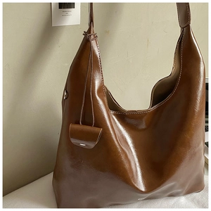 Detail of a shiny brown Hobo tote bag featuring a matching mini accessory pouch on the side