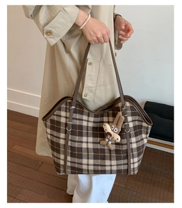 Detail of checkered tote bag featuring a cute plush bunny charm and brown leather straps