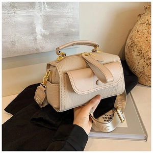 Dettaglio della borsa in pelle beige martellata con finiture dorate e tracolla ampia