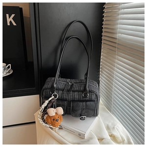 Détail d'un sac oreiller vintage à carreaux avec deux poches et breloque ours