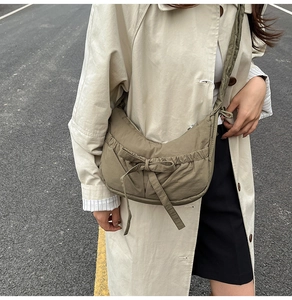 Détail du sac bandoulière croissant kaki avec tissu en nylon plissé et nœud coulissant
