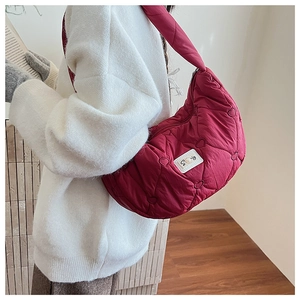 Détail du sac matelassé cœur rouge foncé avec étiquette brodée et bandoulière
