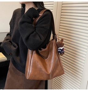 Gros plan du sac hobo marron vintage avec un charm ours dans un décor élégant