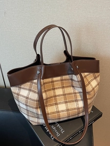 Sac fourre-tout rétro en cuir marron et tissu à carreaux beige sur un livre noir
