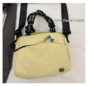 Detailed front zipper pocket on a compact canvas crossbody bag with a lipstick inside