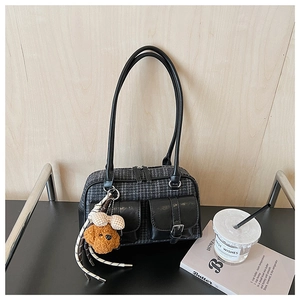 Détail du sac vintage à carreaux gris avec poches en cuir et breloque en peluche