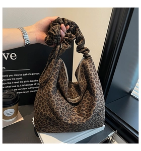 Detail showing the leopard print pattern and unique pleated cloud handle of the tote bag