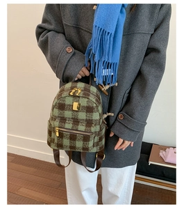 Detail of vintage green plaid wool backpack with golden zippers on a model