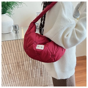 Détail du sac matelassé rouge avec motif cœur et plaque de marque en métal brillant