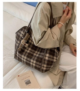 Detail of checkered tote bag with bunny charm on beige coat background