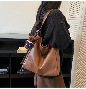Sac seau en cuir mat marron montrant sa grande capacité et son pendentif ours en peluche