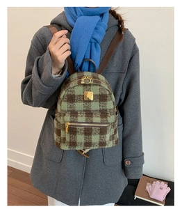 Detail of green and brown plaid wool mini backpack with gold zippers worn by model