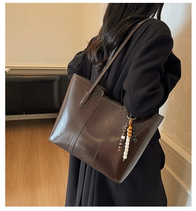 Dettaglio della borsa tote marrone scuro in pelle lucida con ciondolo di perline colorate