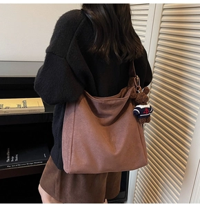 Détail d'un sac seau en daim marron avec un charm ours mignon et une grande capacité