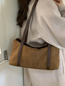 Retro brown suede pillow tote bag with leather straps on model in minimalist coat