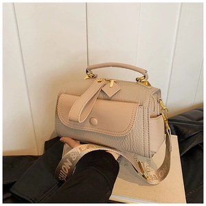 Dettaglio della borsa beige a grana con finiture dorate e tracolla con scritte