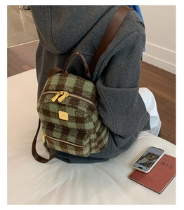 Detail of green and brown checkered mini backpack with tweed texture on grey wool coat