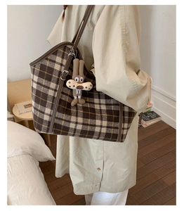 Close-up of tartan tote bag with brown leather straps and cute rabbit plush charm