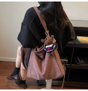 Détail du sac seau en daim marron avec un joli pendentif ours en peluche sur la bandoulière