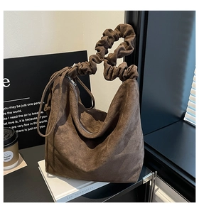 Detail of dark brown suede hobo bag featuring a unique scrunchie handle and silver zipper